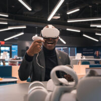 Person using a VR headset and controllers while engaging in an immersive experience at ASU Next Lab.